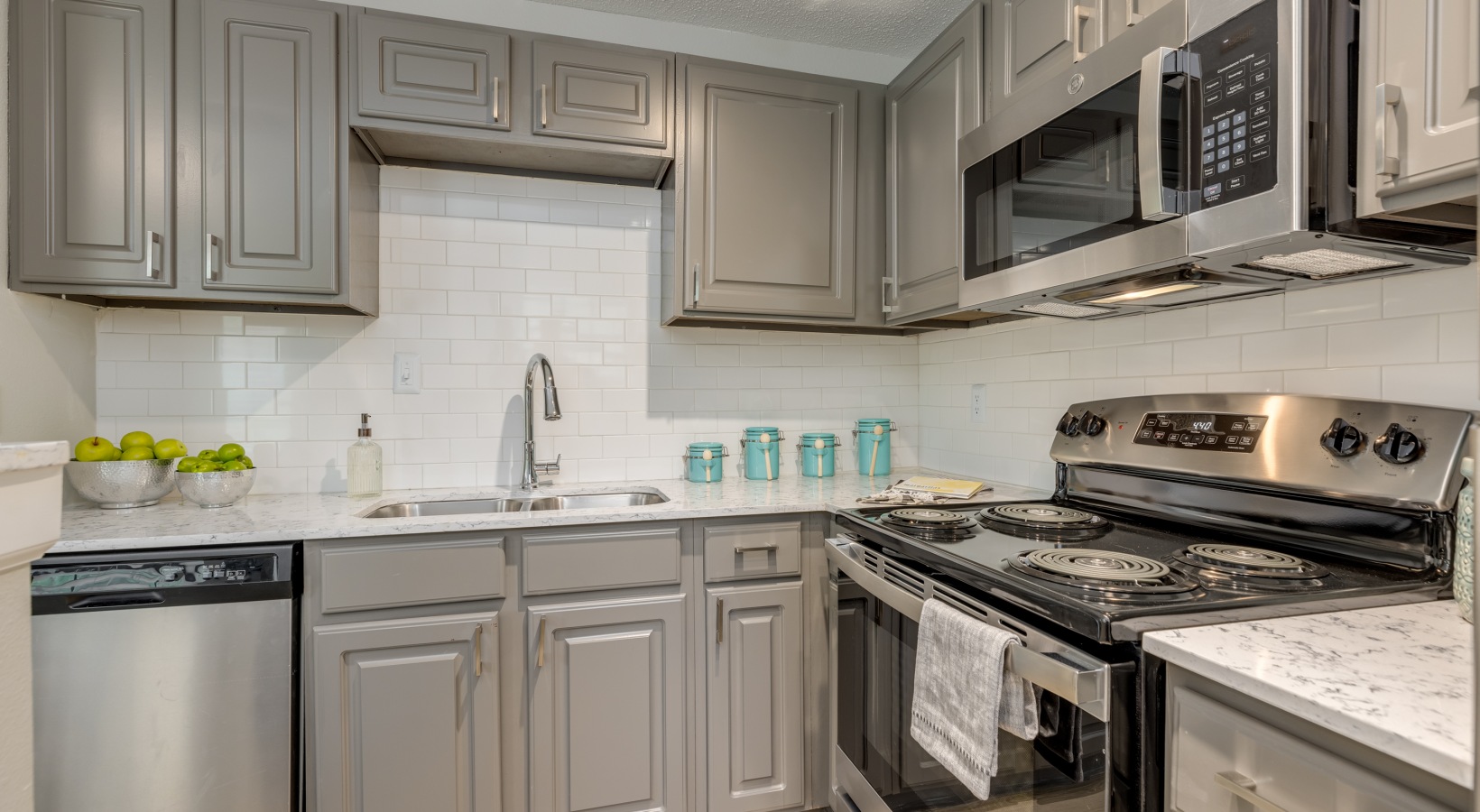 a kitchen with stainless steel appliances and gray cabinets at The  Quinn on Ravenglass