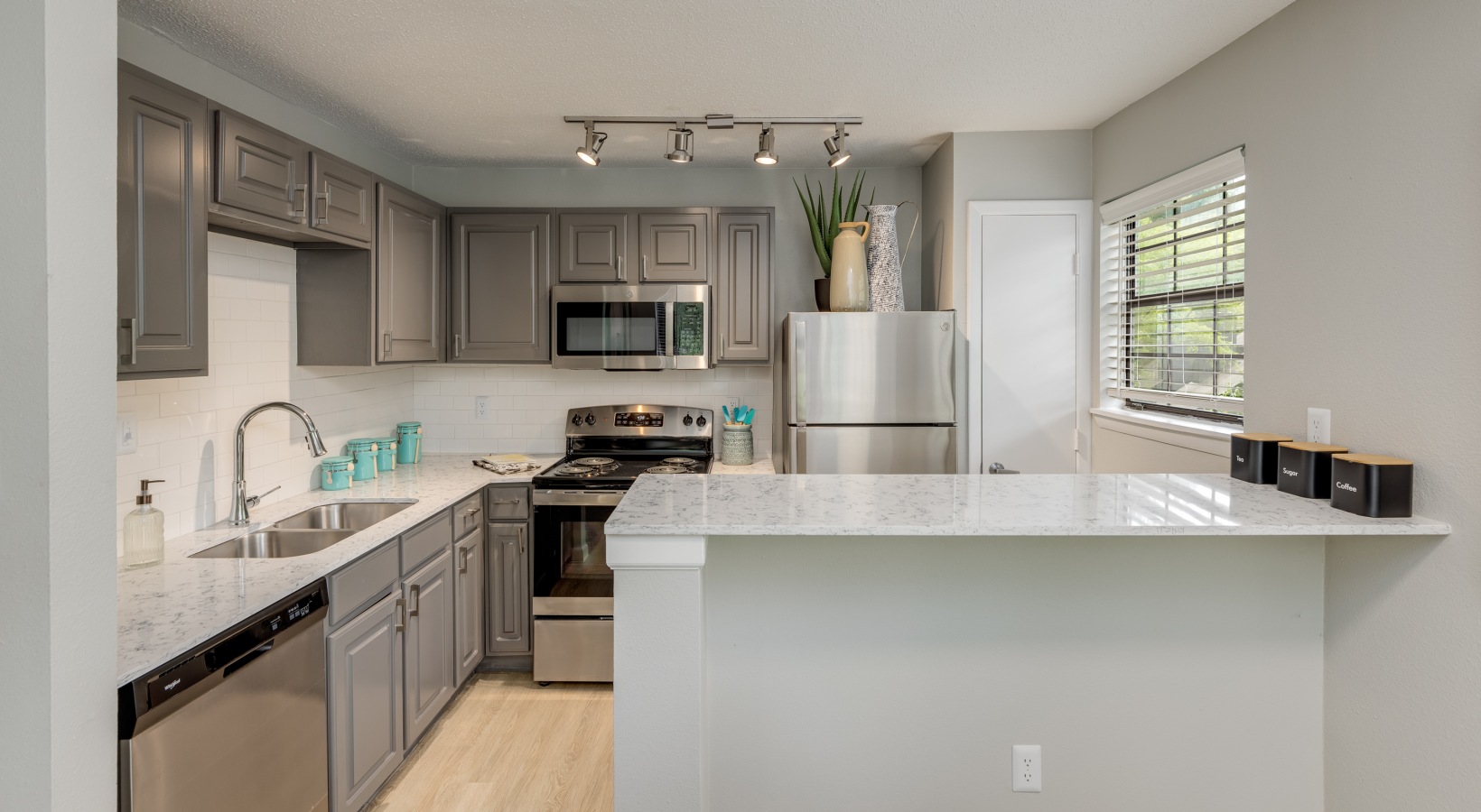 a kitchen with stainless steel appliances and gray cabinets at The  Quinn on Ravenglass