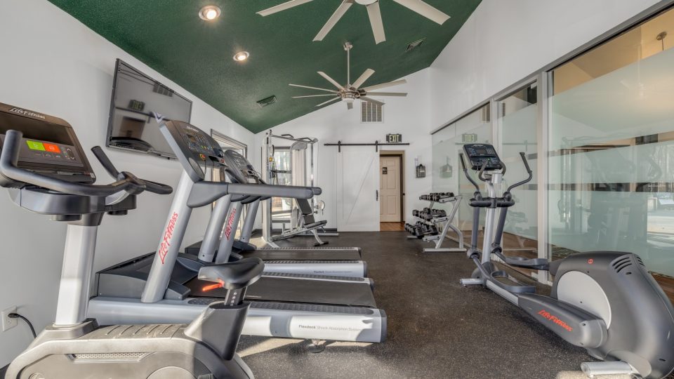 a gym room with tread machines and ceiling fans at The  Quinn on Ravenglass