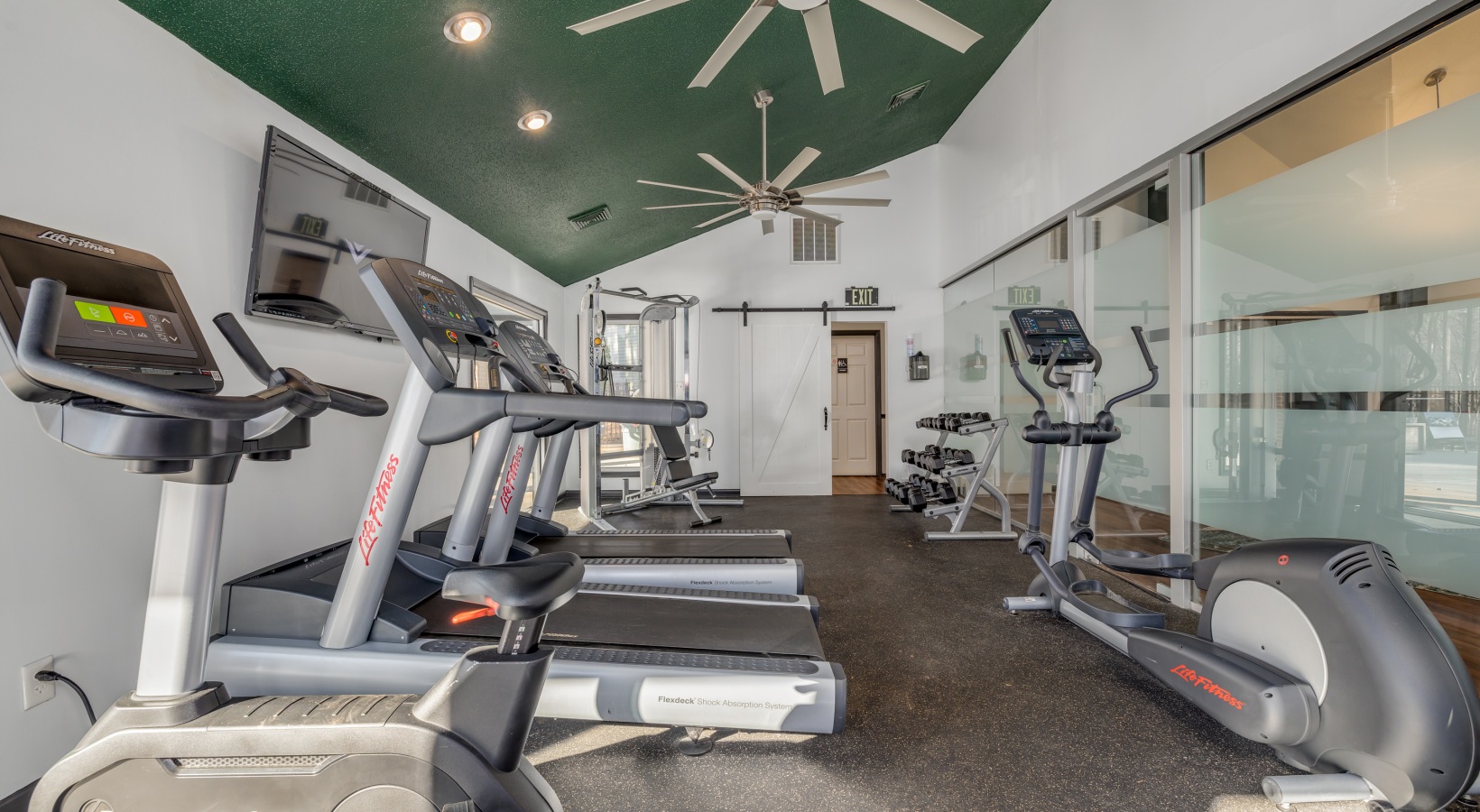 a gym room with tread machines and ceiling fans at The Quinn on Ravenglass